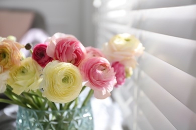 Beautiful ranunculus flowers in vase near window indoors, closeup