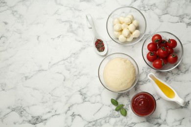 Photo of Raw pizza dough and other ingredients on white marble table, flat lay. Space for text