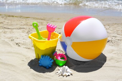 Photo of Set of plastic beach toys and inflatable ball on sand near sea