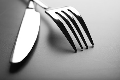Photo of Shiny fork and knife on grey table, closeup
