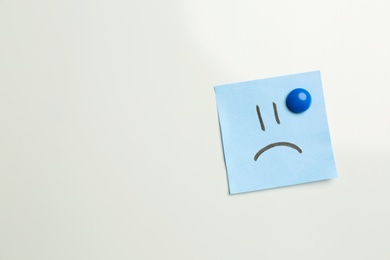 Sticker with sad face on white background, top view. Space for text