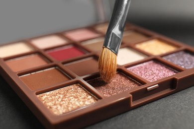 Photo of Colorful eyeshadow palette with brush, closeup view