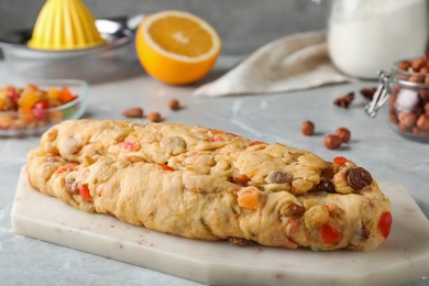 Unbaked Stollen with candied fruits and raisins on light marble table, closeup
