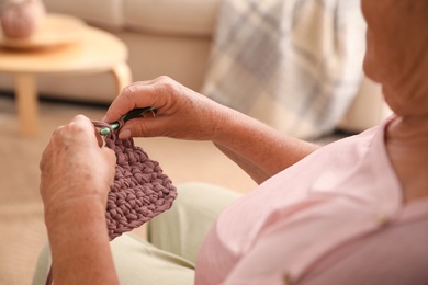 Photo of Elderly woman crocheting at home, closeup. Creative hobby