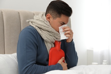 Ill man with hot water bottle at home