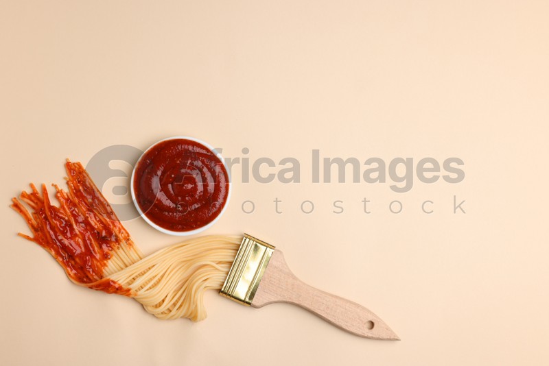 Brush painting with spaghetti dipped in ketchup on beige background, flat lay. Space for text. Creative concept