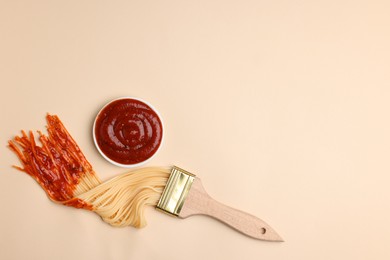 Brush painting with spaghetti dipped in ketchup on beige background, flat lay. Space for text. Creative concept
