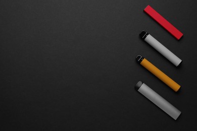 Disposable electronic smoking devices on black background, flat lay. Space for text
