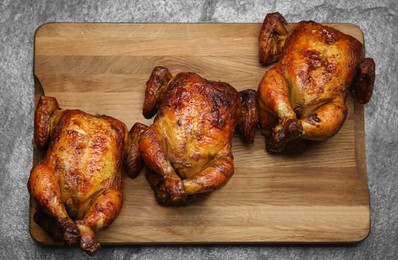 Delicious grilled whole chickens on grey table, top view