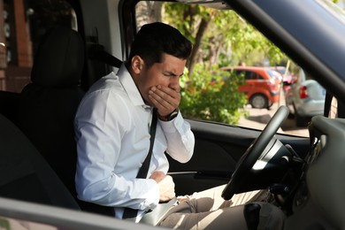 Man suffering from nausea in his car