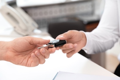 Salesman giving car key to customer in salon
