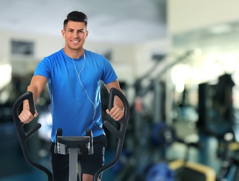 Man using modern elliptical machine in gym, space for text