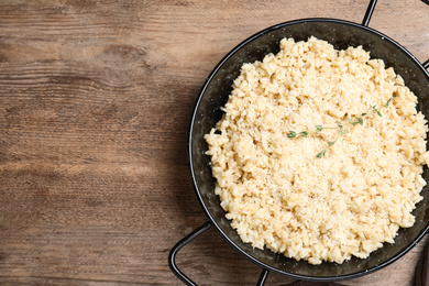 Photo of Delicious risotto with cheese on wooden table, top view. Space for text