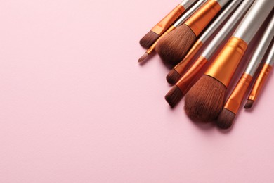 Set of makeup brushes on pink background, above view. Space for text