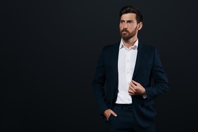 Photo of Portrait of handsome bearded man in suit looking away on black background. Space for text