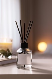 Reed diffuser on white table indoors. Cozy atmosphere