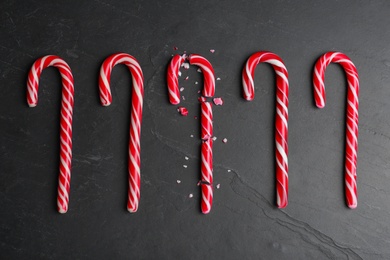 Crushed and whole Christmas candy canes on black background, flat lay