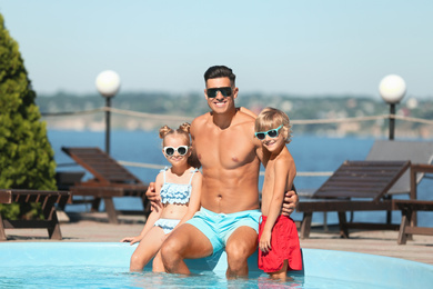 Happy man with his children at poolside on sunny summer day
