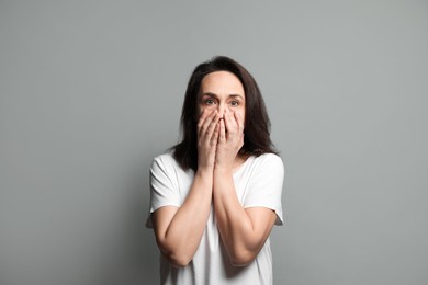 Mature woman feeling fear on grey background