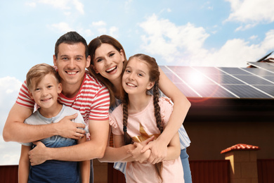Happy family near their house with solar panels. Alternative energy source