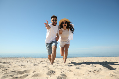 Happy young couple having fun on beach near sea. Honeymoon trip