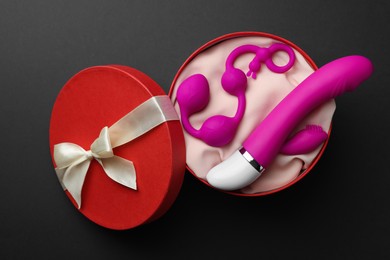 Pink sex toys in gift box on dark blue background, top view