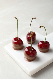 Sweet chocolate dipped cherries on white table