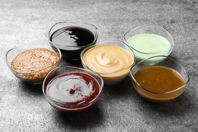 Many bowls with different sauces on grey table