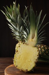 Photo of Whole and cut pineapples on wooden board