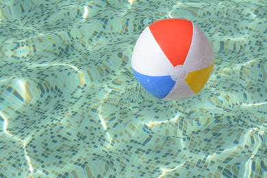 Inflatable beach ball floating in swimming pool, space for text