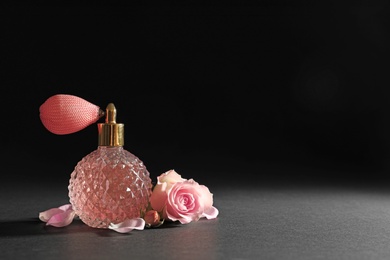 Vintage bottle of perfume and beautiful flower on black background, space for text