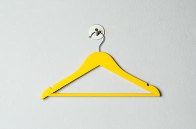 Photo of Empty yellow clothes hanger on white wall