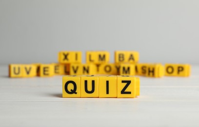 Yellow cubes with word Quiz on white table. Space for text