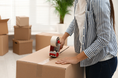 Woman packing cardboard box indoors, closeup. Moving day