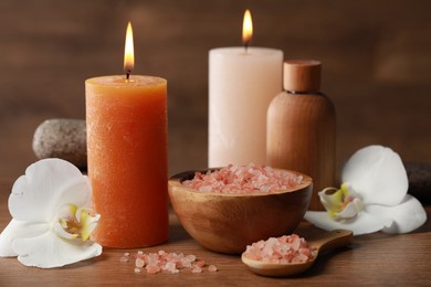 Photo of Beautiful spa composition with sea salt, burning candles and flowers on wooden table, closeup