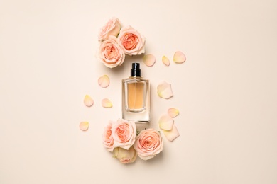 Flat lay composition with bottle of perfume and roses on light background