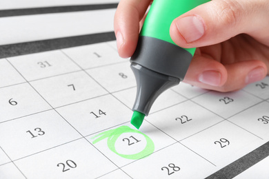Woman marking date in calendar with felt pen, closeup