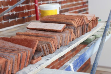 Many decorative bricks on scaffolding indoors. Tiles installation process