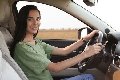 Beautiful young woman on driver's seat in modern car