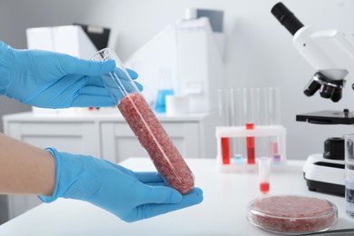 Photo of Scientist holding test tube with minced cultured meat in laboratory, closeup. Space for text