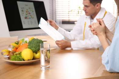 Nutritionist consulting patient at table in clinic, closeup