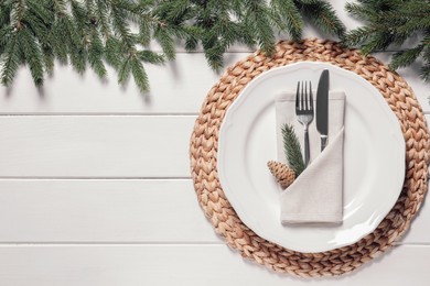 Photo of Beautiful festive place setting with cutlery and fir branches for Christmas dinner on white wooden table, flat lay. Space for text