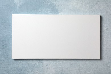 Blank canvas hanging on light blue wall, space for text
