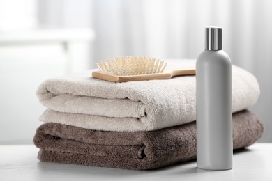 Towels with hair brush and shampoo on table