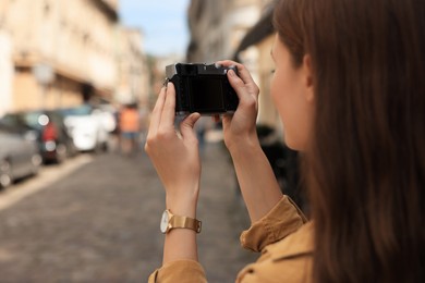 Photo of Young woman with camera taking photo on city street, space for text. Interesting hobby