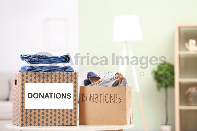 Photo of Donation boxes with clothes and shoes on table indoors