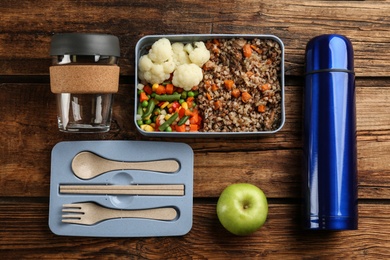 Flat lay composition with thermos and lunch box on wooden background