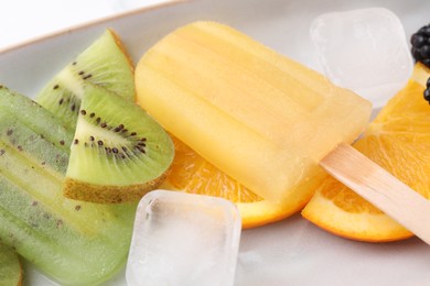Photo of Delicious popsicle, ice cubes and fresh fruits on plate, closeup