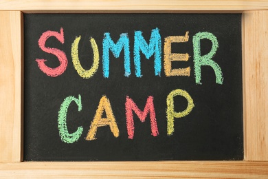 Little blackboard with inscription SUMMER CAMP chalked in different colors, closeup