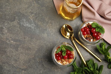 Delicious yogurt parfait with fresh red currants and mint on grey table, flat lay. Space for text